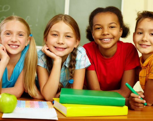 Four Smiling Children with Books and an Apple