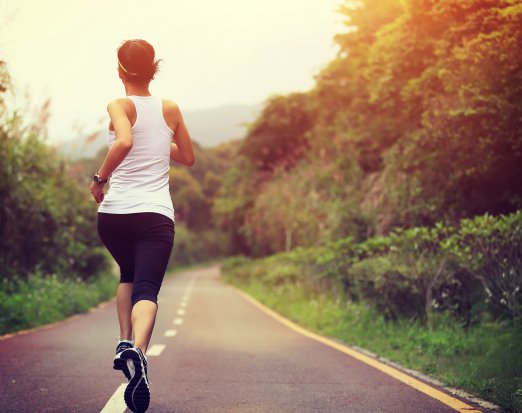 woman jogging down wooded road 