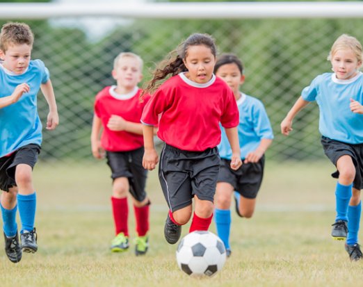 5 Children in Footie Kits Chasing a Football 