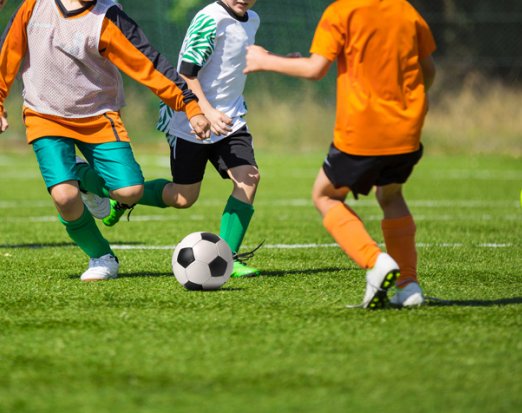 Kids Playing Football on a Pitch