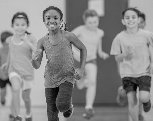 Young Children Smiling and Jogging in Gym Class