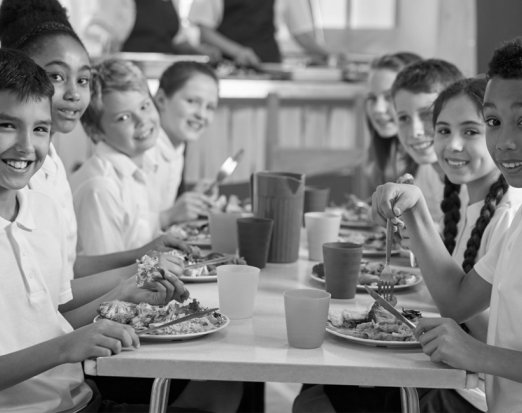 Eight Smiling School Children Eating School Lunch Together