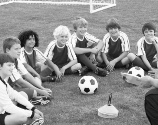 Kids football team sat around a football