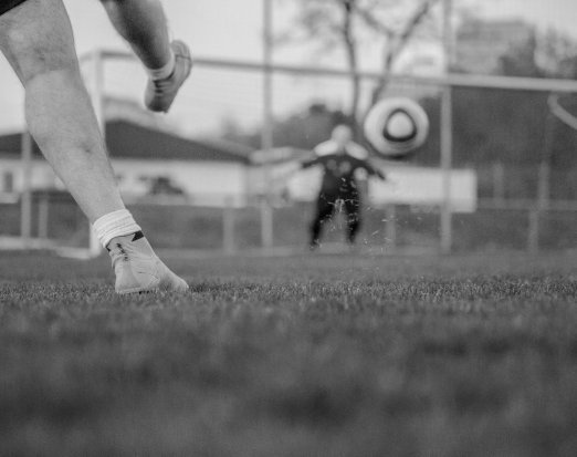 Boy Kicking Football at a Goalie