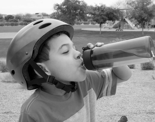 Young Boy in a Blue Bike Helmet Drinking from a Water Bottle