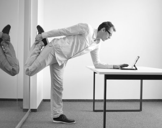 Man in white shirt stretching at desk