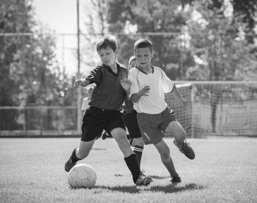 two boys playing football on grass