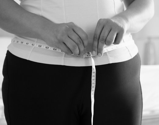 Woman in yellow top measuring waist 