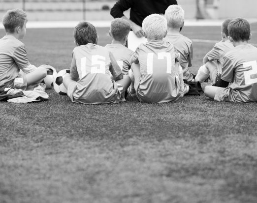 Boys football team sat listening to coach