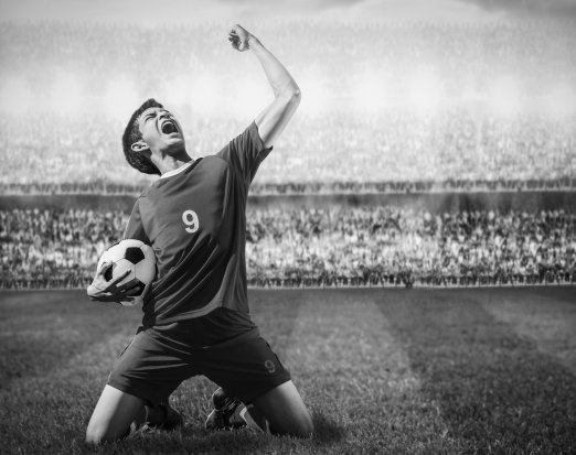 Male footballer celebrating goal infront of crowd