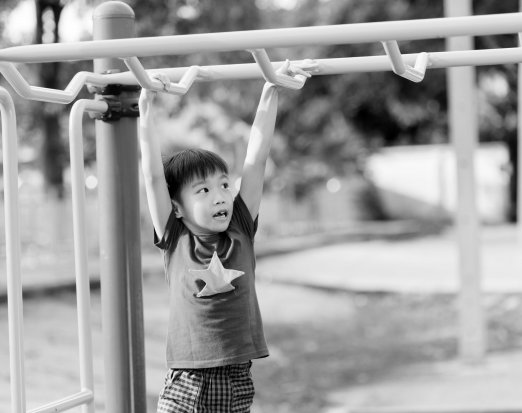 Boy doing monkeybars climbing frame