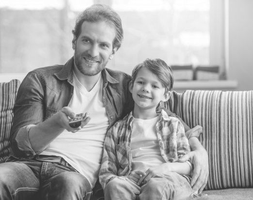 Man and child sat on sofa watching tv