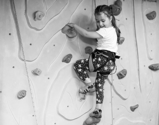 Young girl indoor rock climbing smiling