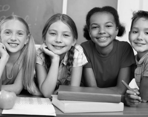 Four Smiling Children with Books and an Apple