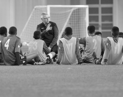 Coach talking to youth football players in front of a goal