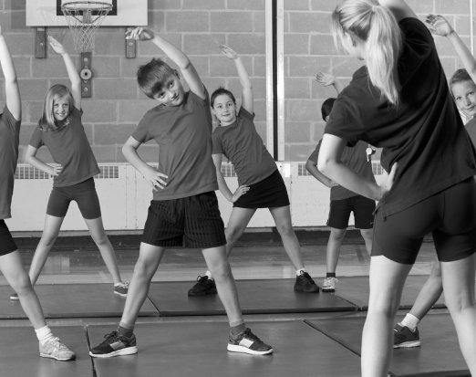 Young Children Stretching in Gym Class