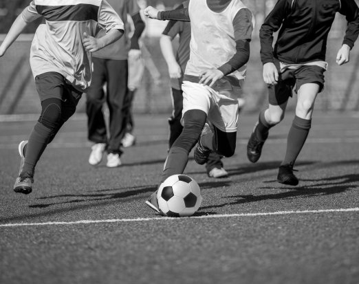 Young boys playing football on pitch Amaven 